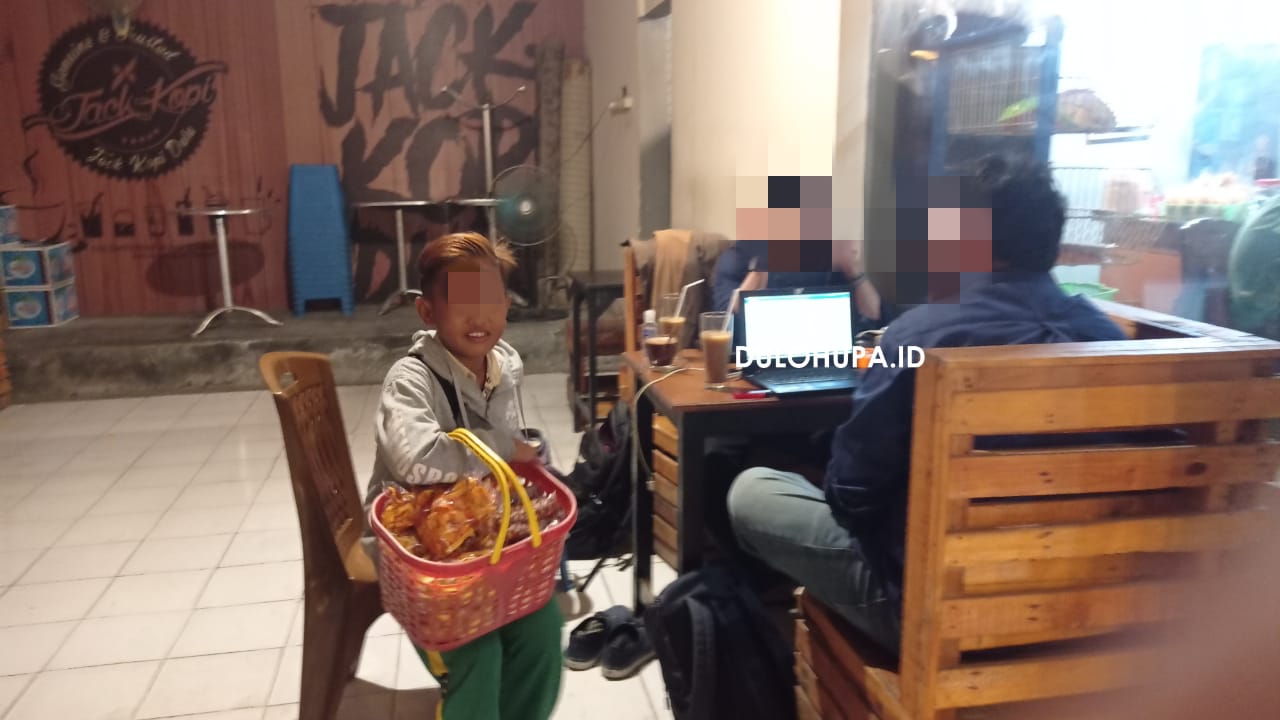 Seorang anak saat menjajakan jualan pada pengunjung warkop di malam hari/Yunita Humola