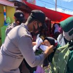 Personel kepolisian memasangkan masker kepada seorang anak pengunjung Pasar Kamis/Reinaldi Julfikar