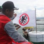 Seorang warga memasang bendera apung yang menjadi tanda bahwa lokasi tangkap gurita ditutup/Japesda