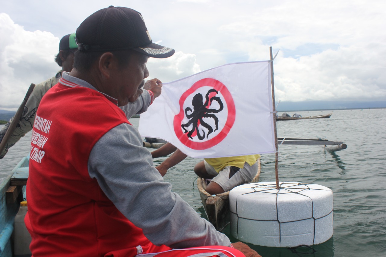 Seorang warga memasang bendera apung yang menjadi tanda bahwa lokasi tangkap gurita ditutup/Japesda