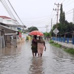 Dua warga berada di tengah banjir/Wawan Akuba