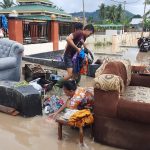 Ibu-ibu yang tampak mencuci pakaian di genangan banjir/Jebeng